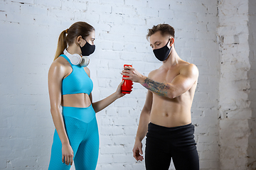Image showing Professional athletes training on brick wall background wearing face mask. Sport during quarantine