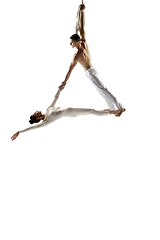 Image showing Couple of young acrobats, circus athletes isolated on white studio background. Training perfect balanced in flight