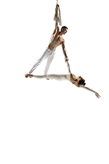 Image showing Couple of young acrobats, circus athletes isolated on white studio background. Training perfect balanced in flight