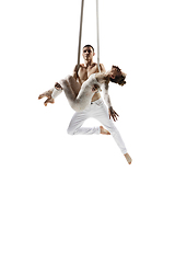 Image showing Couple of young acrobats, circus athletes isolated on white studio background. Training perfect balanced in flight