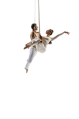 Image showing Couple of young acrobats, circus athletes isolated on white studio background. Training perfect balanced in flight