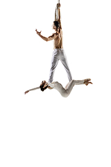 Image showing Couple of young acrobats, circus athletes isolated on white studio background. Training perfect balanced in flight