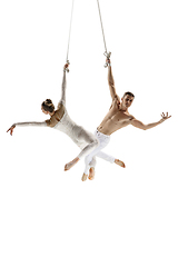 Image showing Couple of young acrobats, circus athletes isolated on white studio background. Training perfect balanced in flight