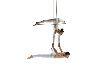 Image showing Couple of young acrobats, circus athletes isolated on white studio background. Training perfect balanced in flight