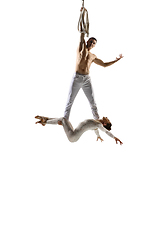 Image showing Couple of young acrobats, circus athletes isolated on white studio background. Training perfect balanced in flight