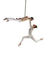 Image showing Couple of young acrobats, circus athletes isolated on white studio background. Training perfect balanced in flight