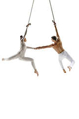 Image showing Couple of young acrobats, circus athletes isolated on white studio background. Training perfect balanced in flight