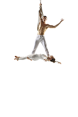 Image showing Couple of young acrobats, circus athletes isolated on white studio background. Training perfect balanced in flight