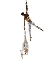 Image showing Couple of young acrobats, circus athletes isolated on white studio background. Training perfect balanced in flight
