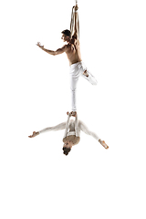 Image showing Couple of young acrobats, circus athletes isolated on white studio background. Training perfect balanced in flight