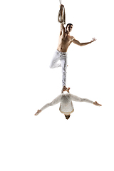 Image showing Couple of young acrobats, circus athletes isolated on white studio background. Training perfect balanced in flight