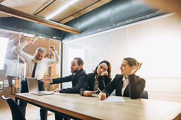 Image showing Angry boss with megaphone screaming at employees in office, scared and annoyed colleagues listening at the table