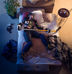 Image showing Top view of young professional hockey player sleeping at his bedroom in sportwear with equipment