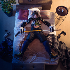 Image showing Top view of young professional hockey player sleeping at his bedroom in sportwear with equipment