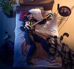 Image showing Top view of young professional hockey player sleeping at his bedroom in sportwear with equipment