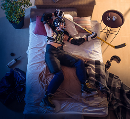 Image showing Top view of young professional hockey player sleeping at his bedroom in sportwear with equipment