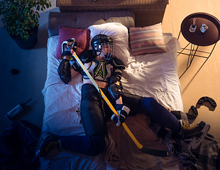 Image showing Top view of young professional hockey player sleeping at his bedroom in sportwear with equipment