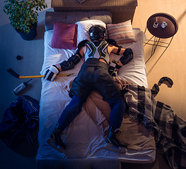 Image showing Top view of young professional hockey player sleeping at his bedroom in sportwear with equipment