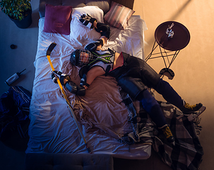 Image showing Top view of young professional hockey player sleeping at his bedroom in sportwear with equipment