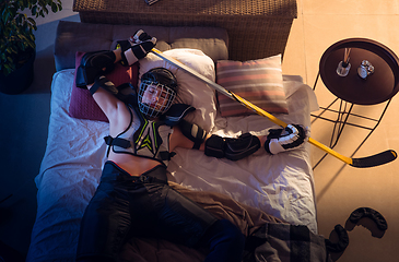 Image showing Top view of young professional hockey player sleeping at his bedroom in sportwear with equipment