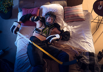 Image showing Top view of young professional hockey player sleeping at his bedroom in sportwear with equipment