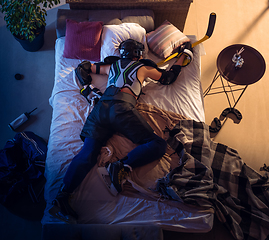 Image showing Top view of young professional hockey player sleeping at his bedroom in sportwear with equipment