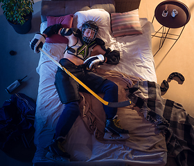Image showing Top view of young professional hockey player sleeping at his bedroom in sportwear with equipment