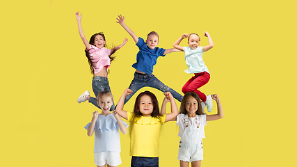 Image showing Portrait of little children jumping isolated on yellow studio background with copyspace