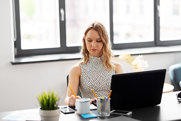 Image showing businesswoman writing to notebook at office