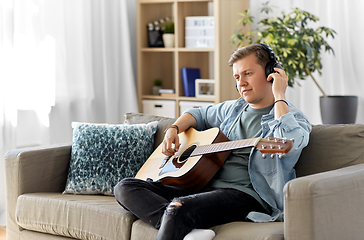 Image showing man in headphones playing guitar at home