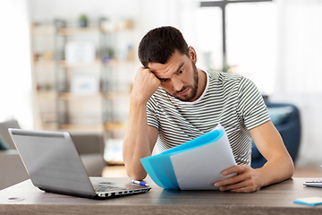 Image showing man with papers and laptop working at home office