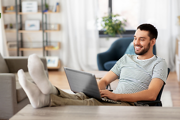 Image showing man with laptop resting feet on table at home
