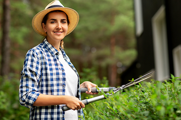 Image showing woman with pruner cutting branches at garden