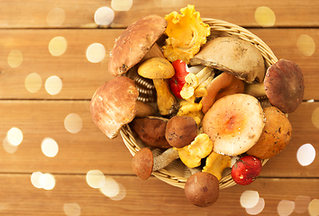 Image showing basket of different edible mushrooms on wood