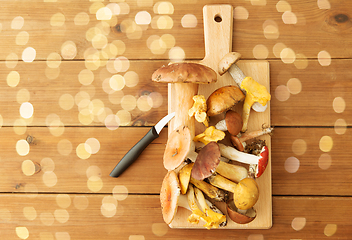 Image showing edible mushrooms on wooden cutting board and knife