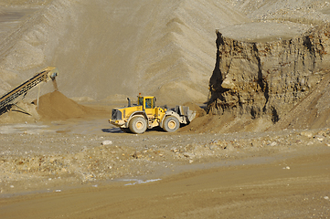 Image showing A yellow wheel loader is working in gravel pit