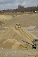 Image showing A yellow wheel loader is working in gravel pit