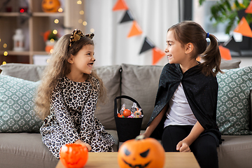 Image showing girls in halloween costumes with candies at home