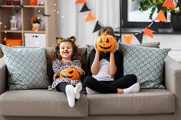 Image showing girls in halloween costumes with pumpkins at home