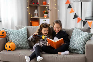 Image showing girls in halloween costumes reading book at home