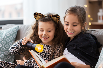 Image showing girls in halloween costumes reading book at home