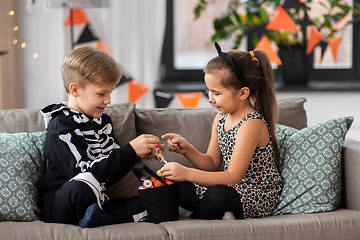 Image showing kids in halloween costumes with candies at home