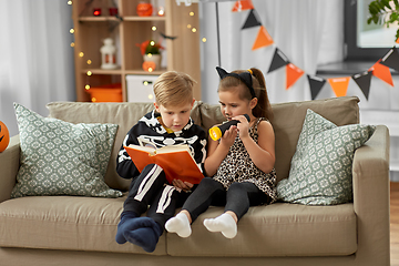 Image showing kids in halloween costumes reading book at home