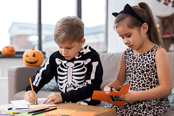 Image showing kids in halloween costumes doing crafts at home