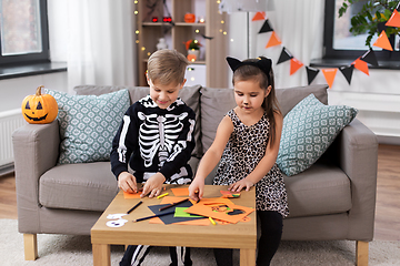 Image showing kids in halloween costumes doing crafts at home