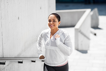 Image showing african american woman running upstairs outdoors