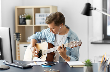 Image showing man with earphones and smartphone playing guitar
