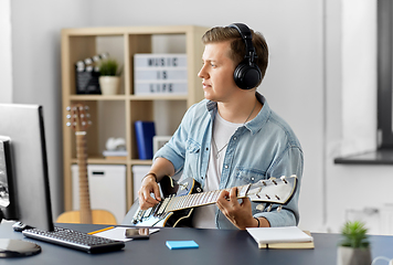 Image showing man in headphones playing bass guitar at home