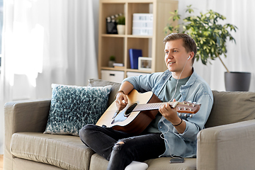 Image showing man with guitar, earphones and smartphone at home