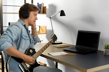 Image showing man in headphones playing bass guitar at home